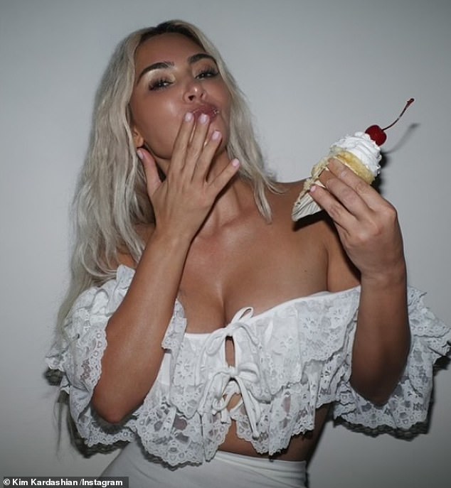 Kim Kardashian was scarfing down a vanilla cupcake with a cherry on top in new images shared to Instagram on Friday. The 43-year-old reality TV star was wearing an off-the shoulder cream top